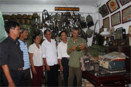 Cựu chiến binh Bùi Đình Thu (ngoài cùng, bên phải) giới thiệu các kỷ vật chiến tranh với người dân đến tham quan.