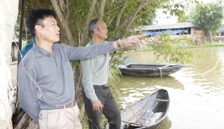 Anh Lê Văn Tiên (trái) trao đổi công việc cùng anh trai Lê Văn Diện bên hồ cá. 